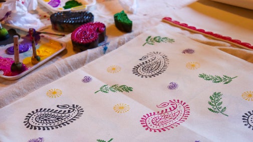 Woodblock prints being used to print colourful paints onto a piece of fabric